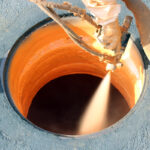Polyurea spray lining being applied inside a manhole - manhole rehabilitation process